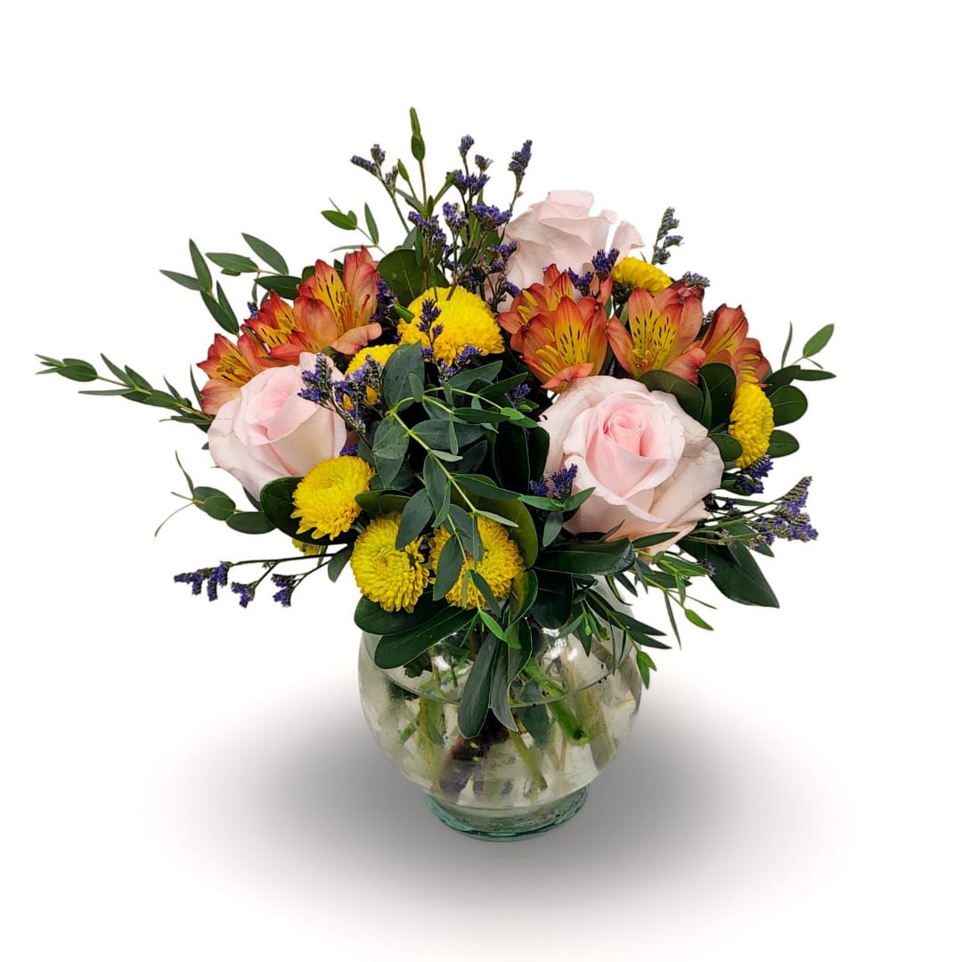 Mixed bouquet of pink roses, yellow mums, and orange alstroemeria in a glass vase