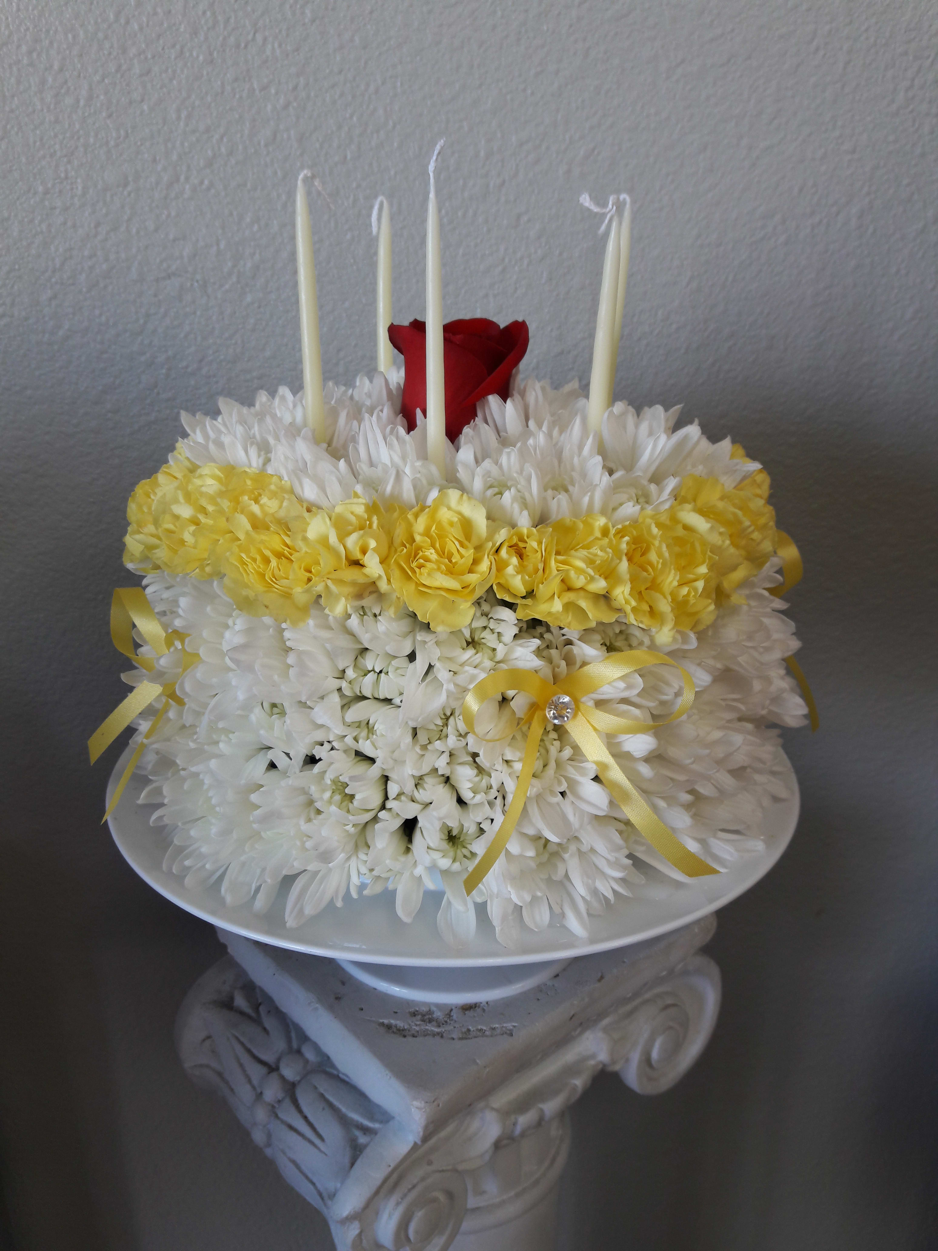White and yellow floral arrangement with red roses and tall white candles