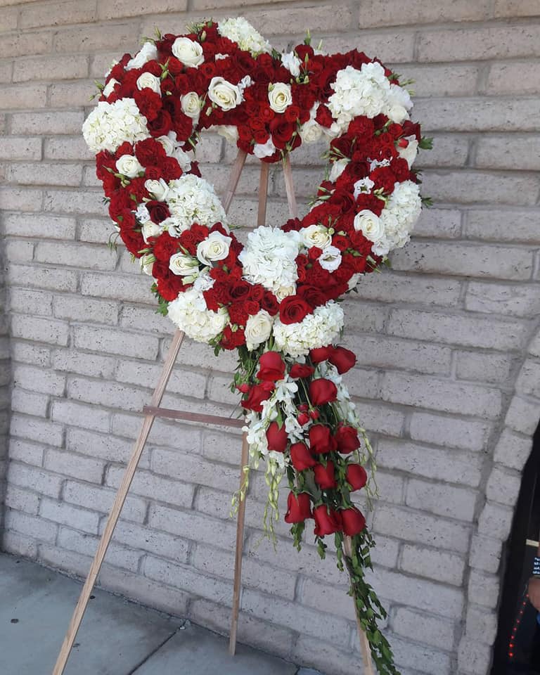 Heart-shaped floral wreath of red and white roses on an easel