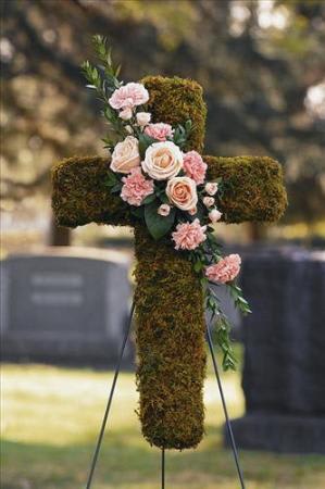 Moss-covered cross with pink flowers on a stand