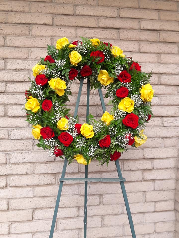 Circular wreath of red and yellow roses on a stand