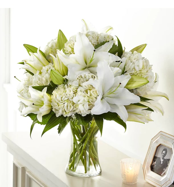 White lilies and hydrangeas in a clear glass vase