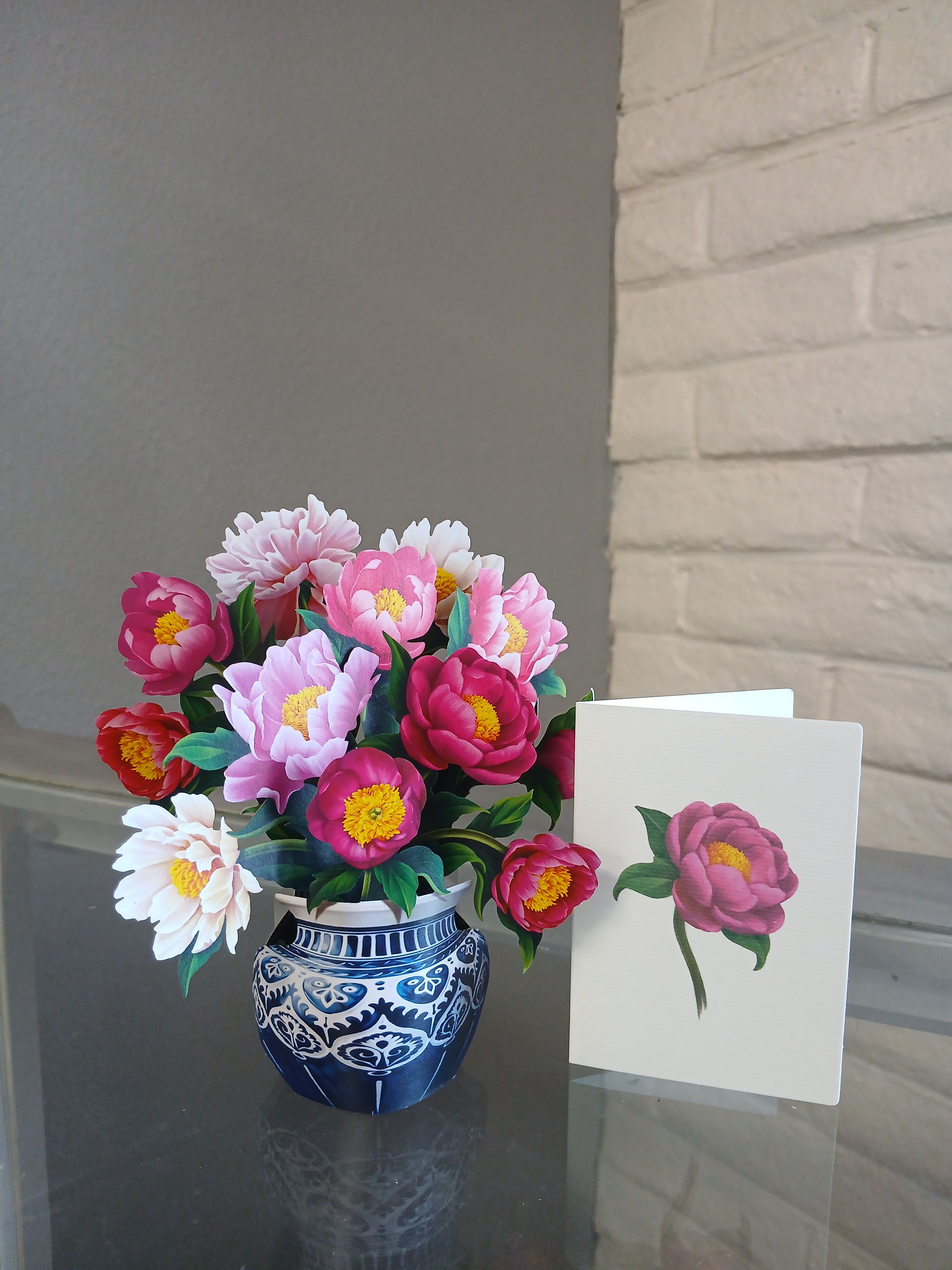 Mini Peony  -  The Mini Peony. Featuring a delightful assortment of rich pink hues in paper peony blossoms, our paper flower bouquet includes an indigo and white patterned pot and a matching blank notecard. Come in a beautiful Envelope that matches  