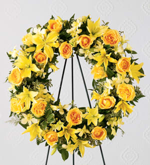 Yellow rose and lily wreath on a black stand