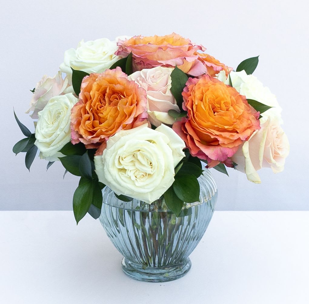 Bouquet of orange, pink, and white roses in a glass vase