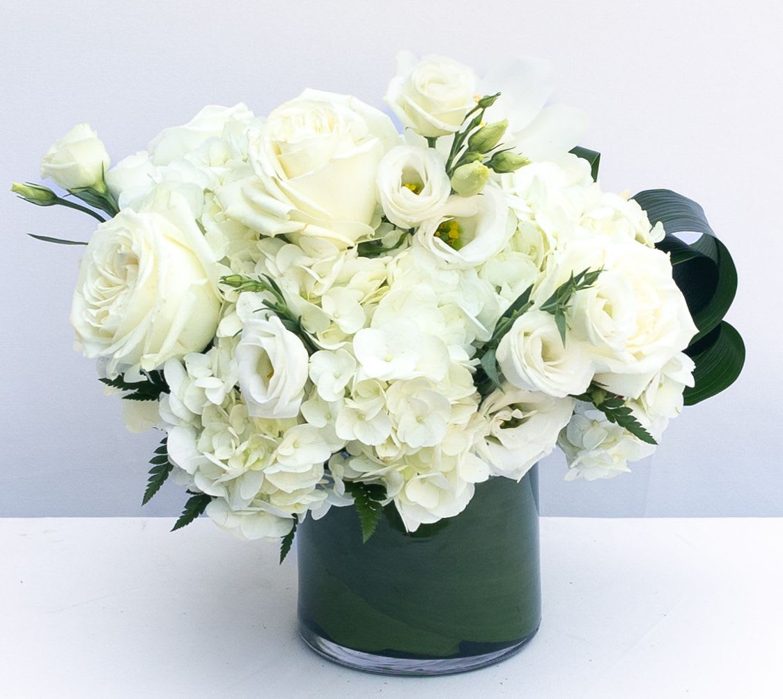 White roses and hydrangeas arranged in a dark green vase