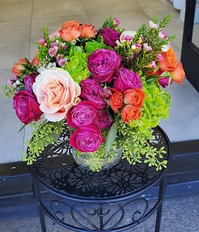 You smile &amp; I'll smile    - This vibrant, full-rounded bouquet features a lush mix of orange, coral, and magenta spray roses complemented by fresh green hydrangeas. Artfully arranged in a clear glass vase, this colorful centerpiece is the perfect way to brighten any room or celebrate a special occasion.
