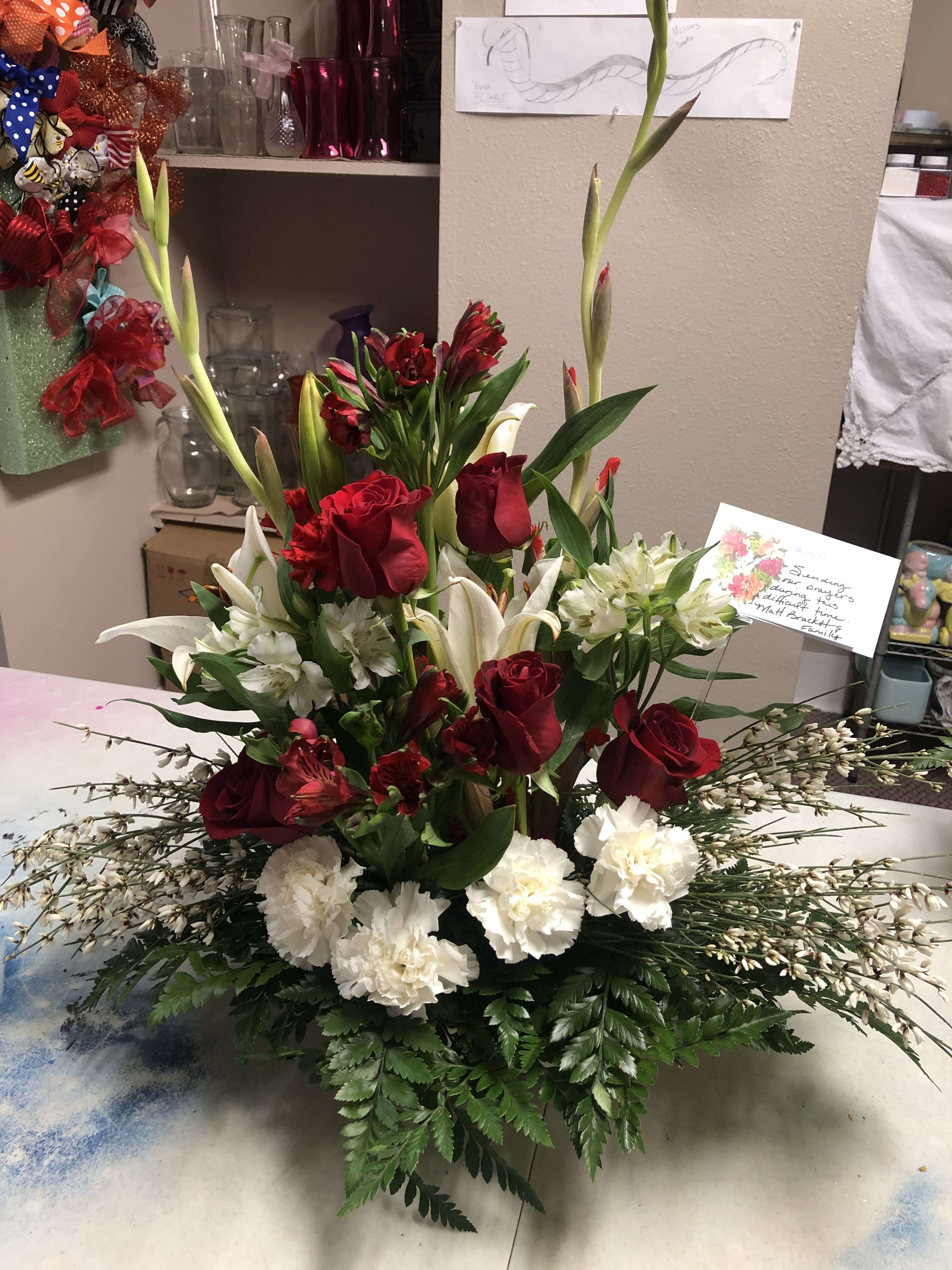 Tall red and white floral arrangement with roses, lilies, and carnations