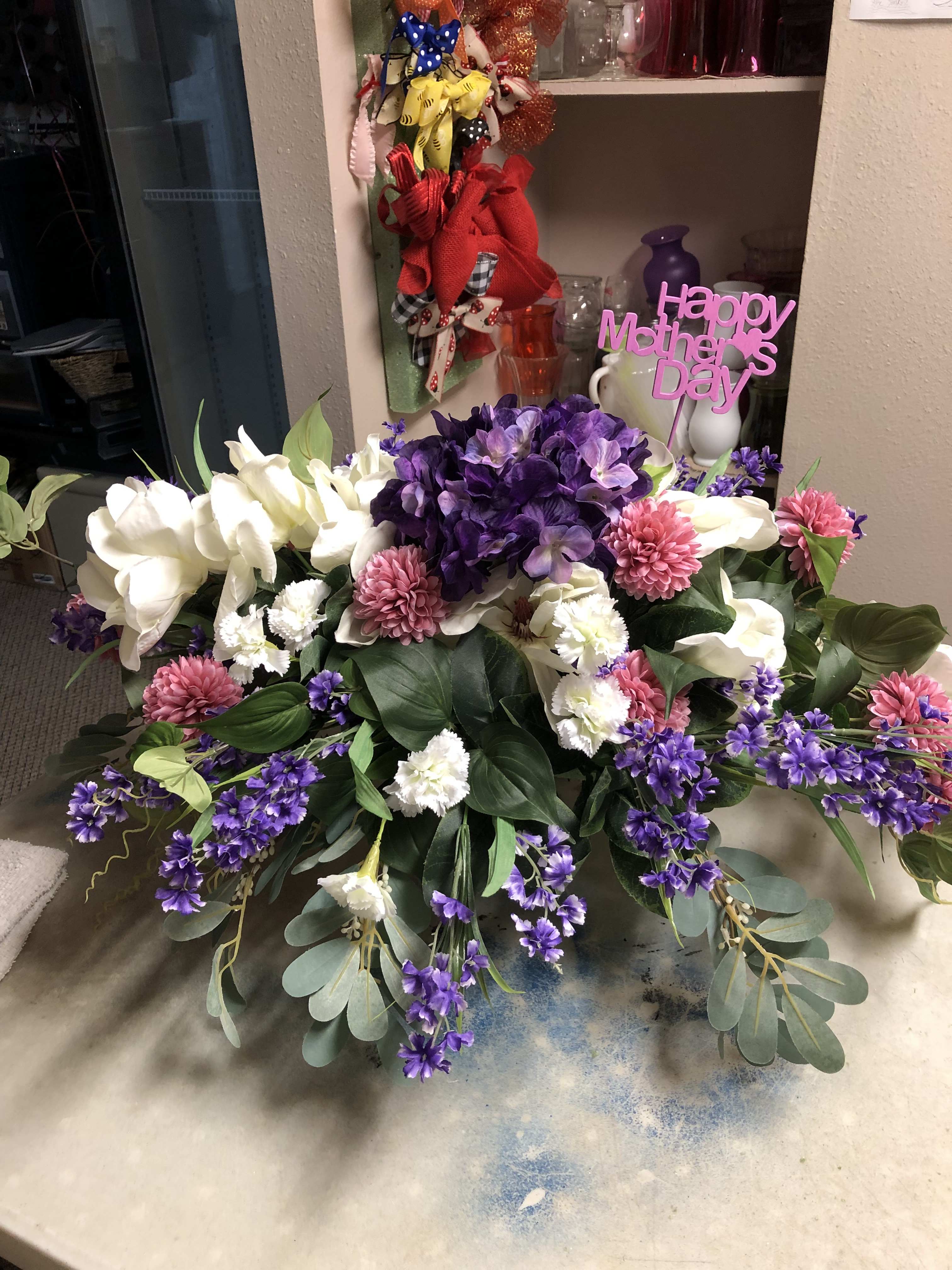 Large purple, white, and pink floral arrangement with a Happy Mother's Day sign