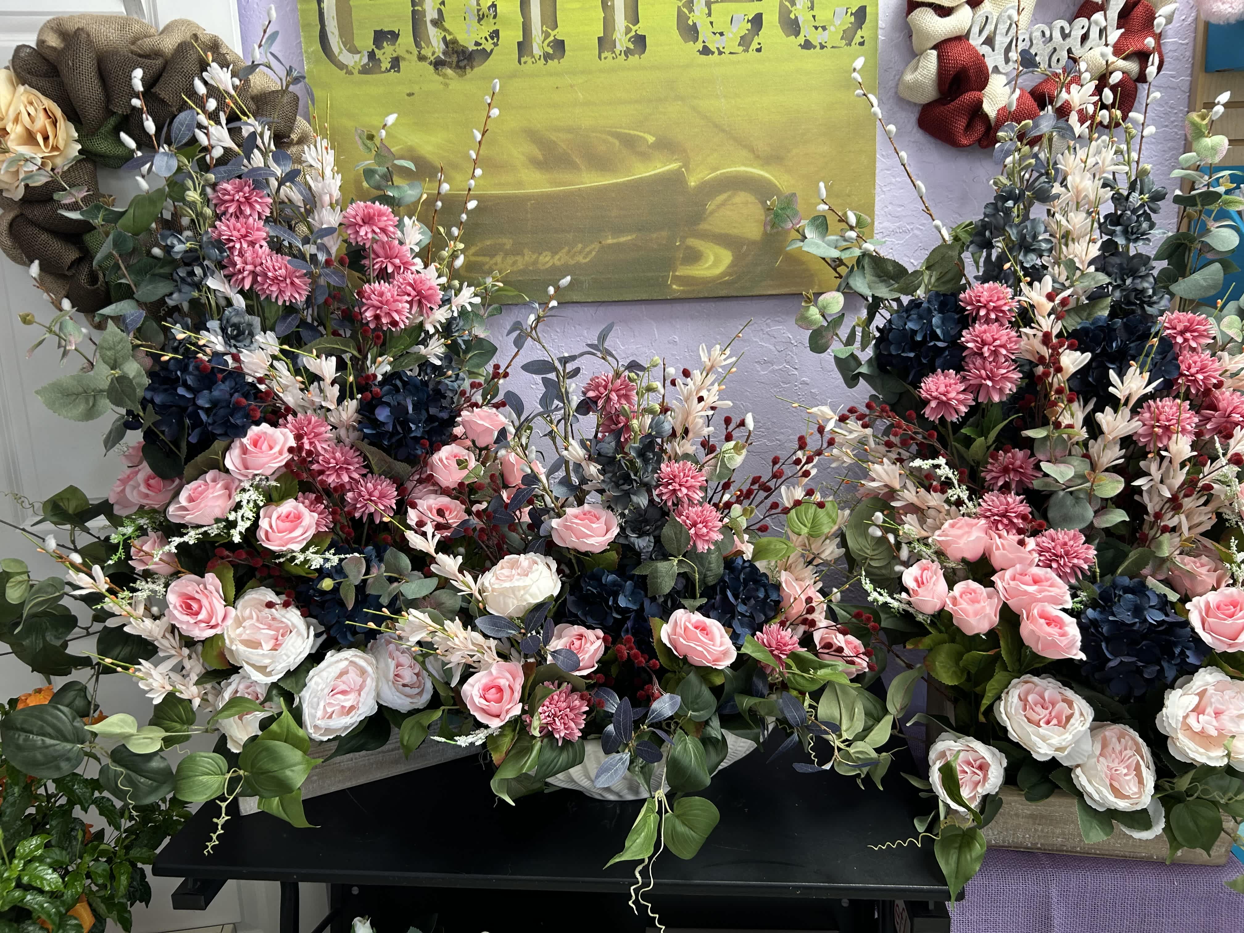 Three large floral arrangements with pink and white roses and dark blue blooms.