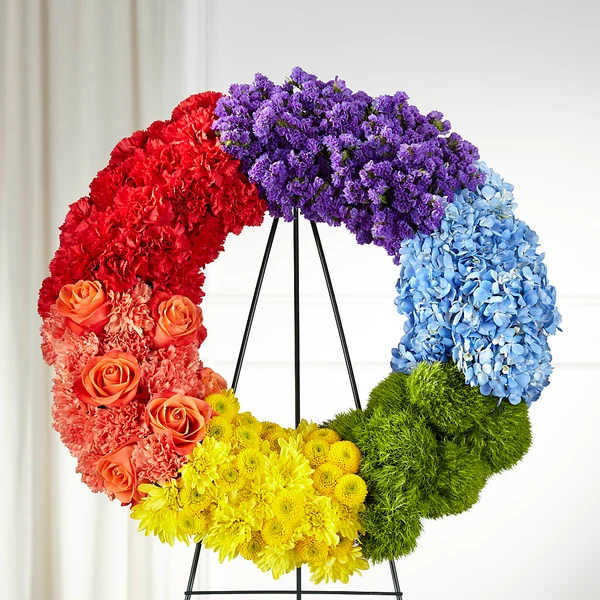 Rainbow floral wreath on a black stand with red, purple, blue, yellow, and green sections