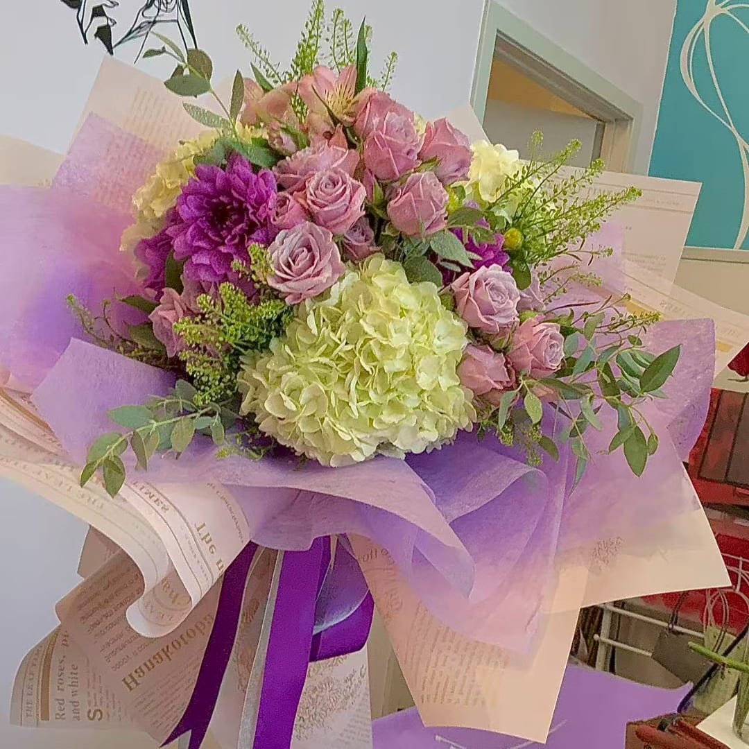 Bouquet of pink roses and hydrangeas wrapped in lavender paper