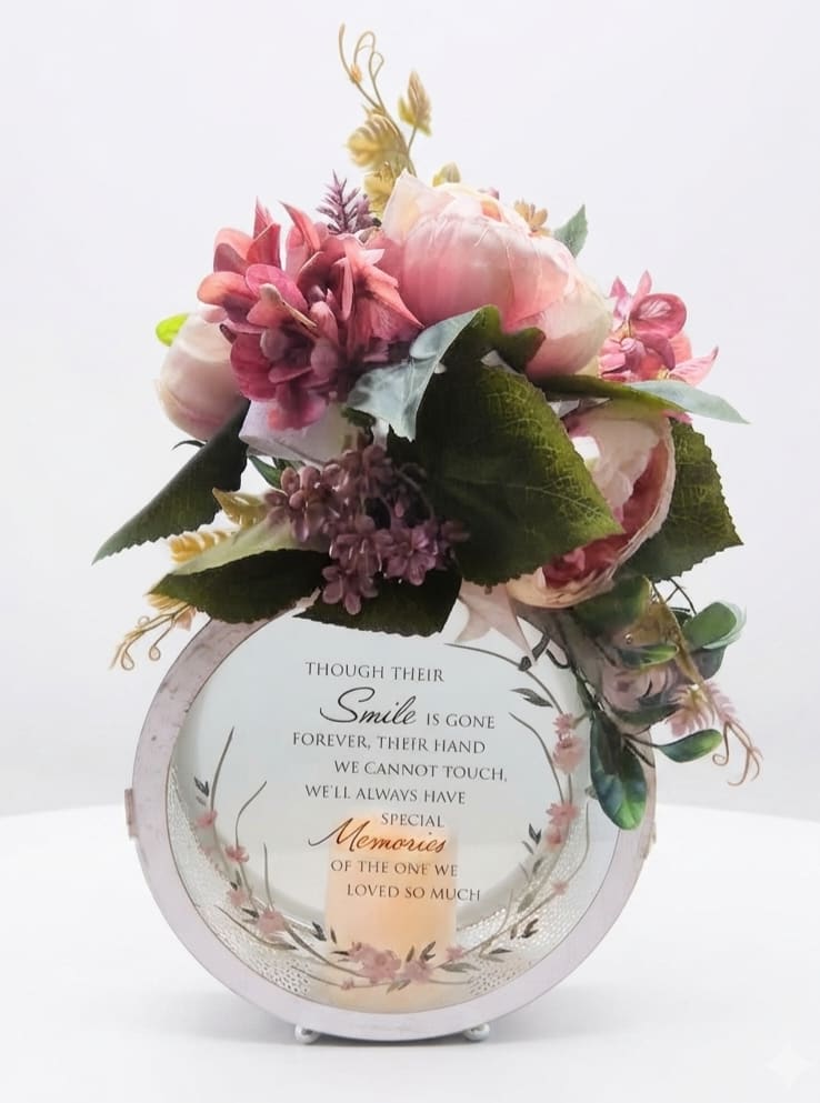 Pink floral arrangement on a memorial plaque with a candle graphic