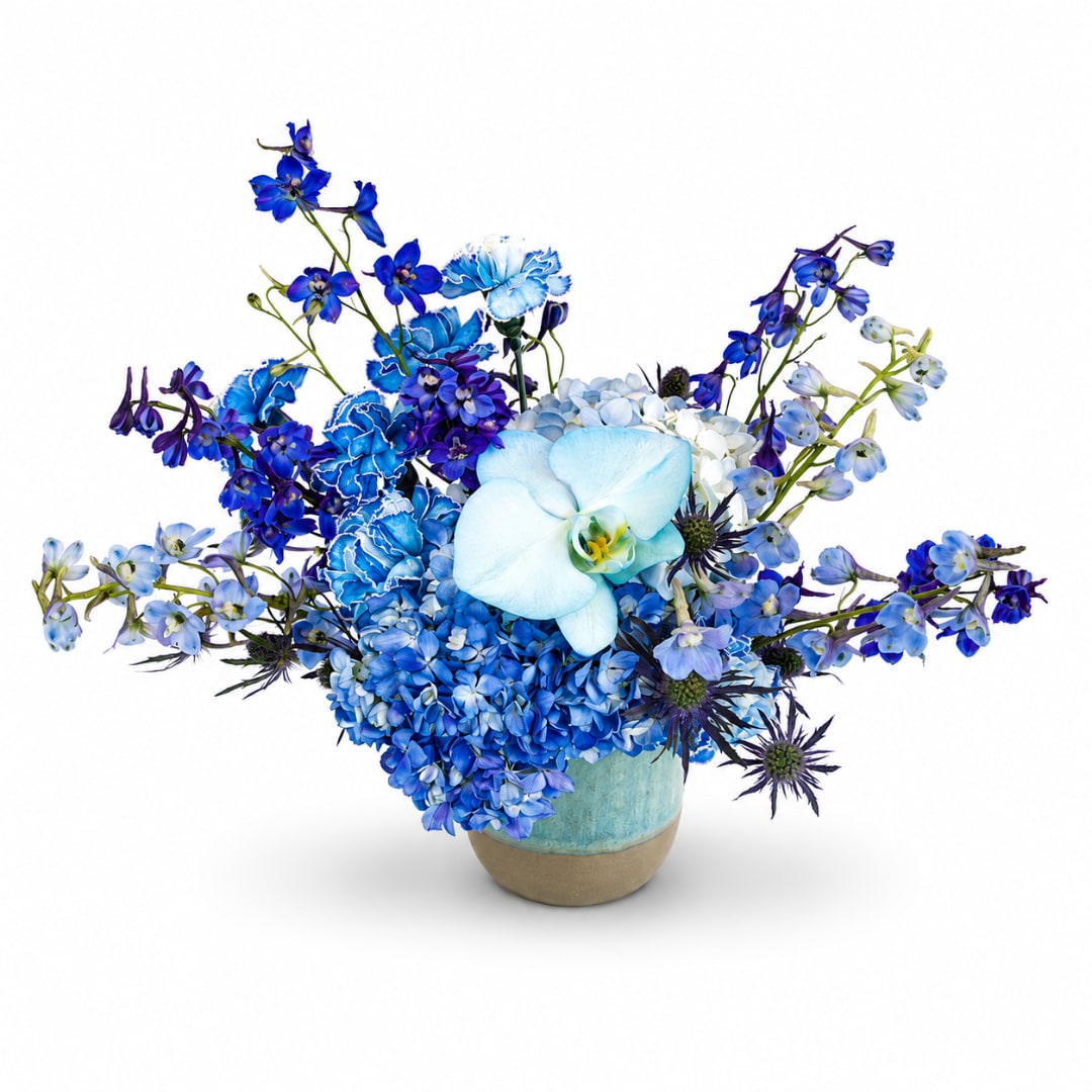 Blue floral arrangement in a ceramic vase with orchids and hydrangeas