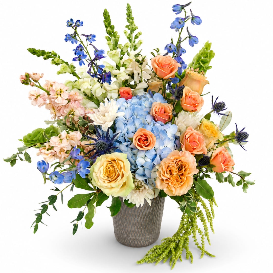 Mixed bouquet of blue, peach, and white flowers in a textured vase