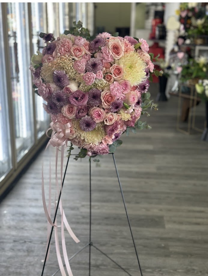 Heart-shaped bouquet of pink and purple flowers on a stand