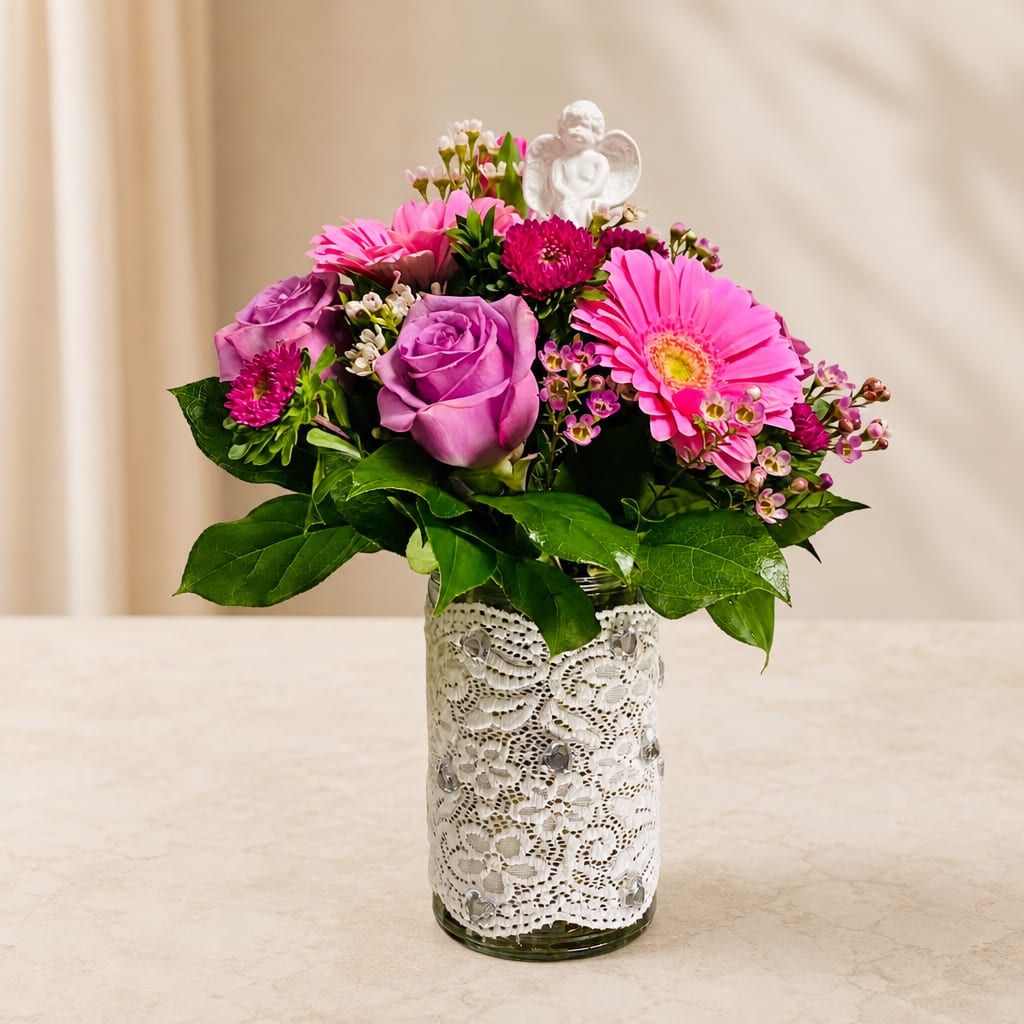 Pink and purple flower arrangement in a lace-wrapped glass vase