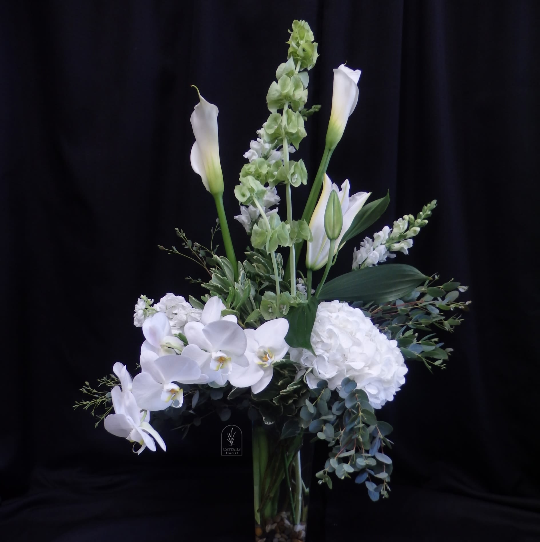 Waterfall - "Waterfall"  is a contemporary style all white arrangement, featuring fluffy white hydrangeas, calla lilies, exquisite orchids and bells of Ireland. It's style is characterized by its elegant, flowing design of flowers and foliage, mimicking the natural flow of a waterfall.