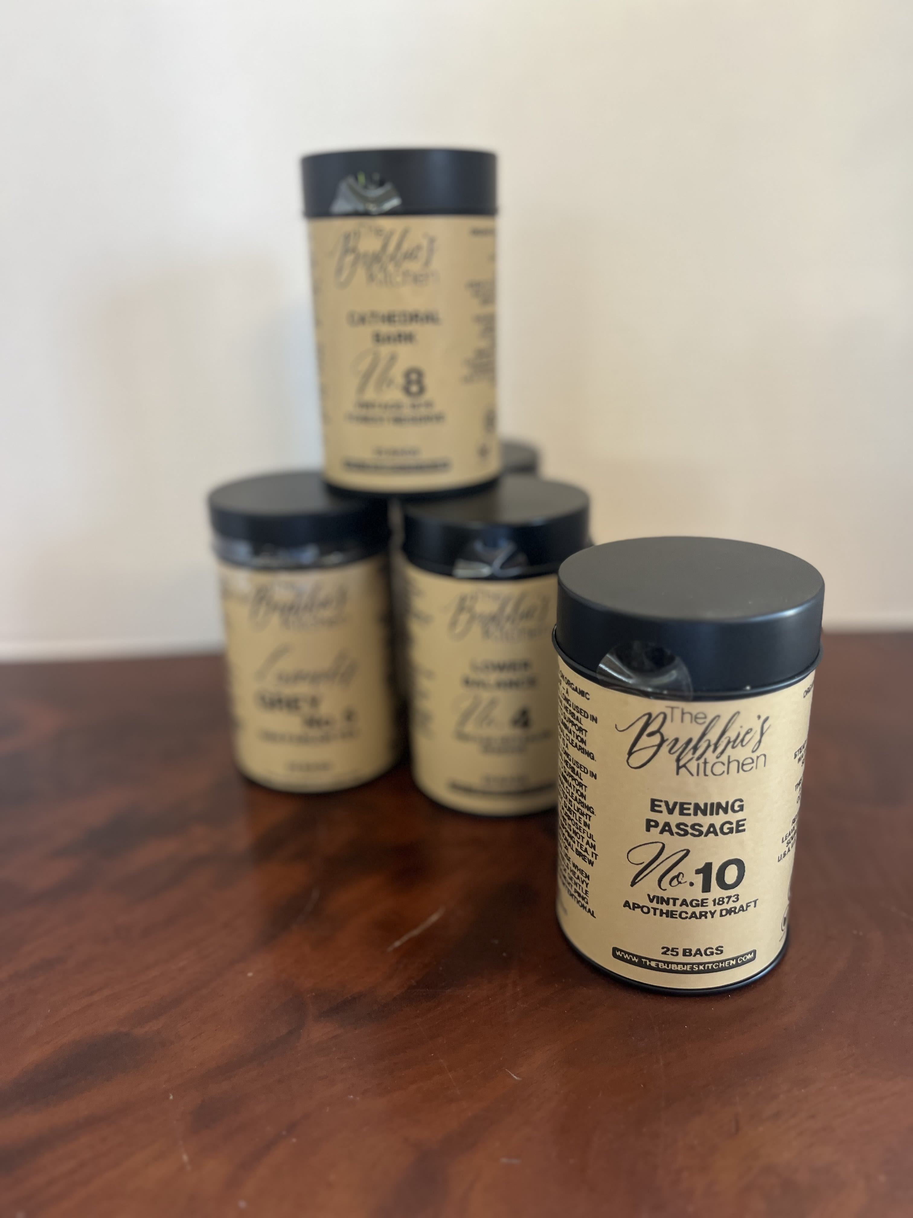 Set of four tan and black cylindrical canisters arranged on a wooden surface