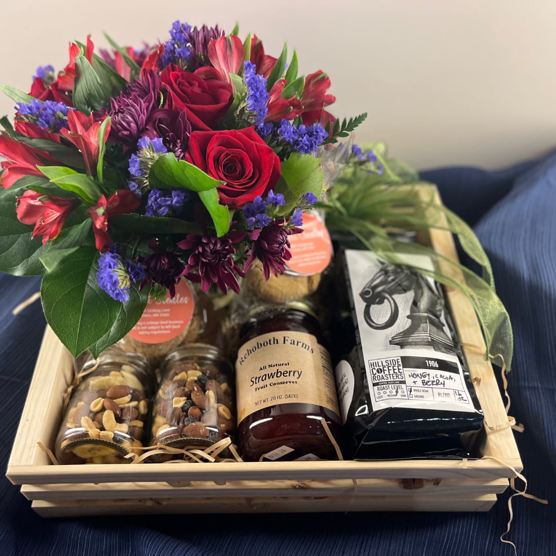 Gift basket with a mixed flower bouquet, jam jars, nuts, and coffee