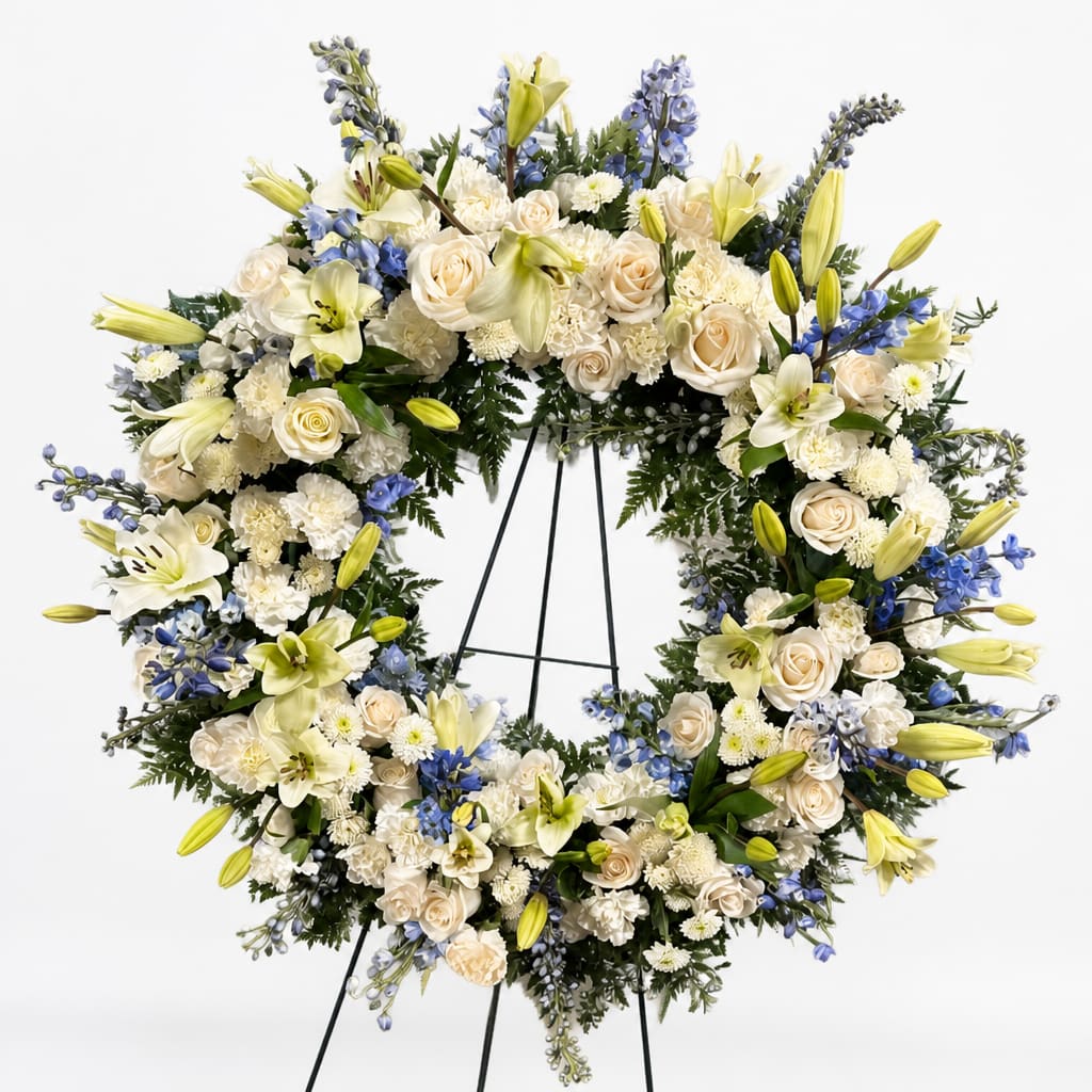 Large white floral wreath on a black stand with cream and blue flowers