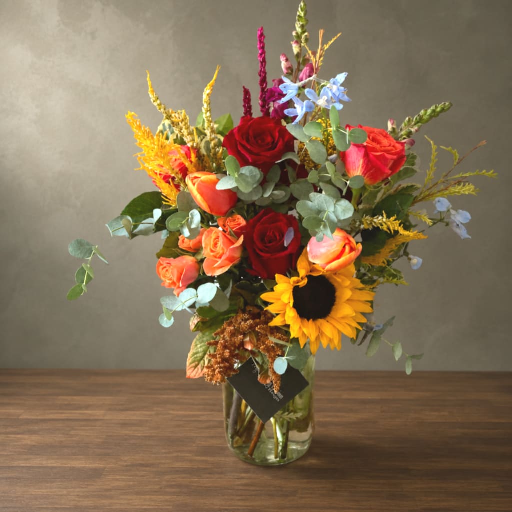 Mixed bouquet of roses and a sunflower in a glass vase