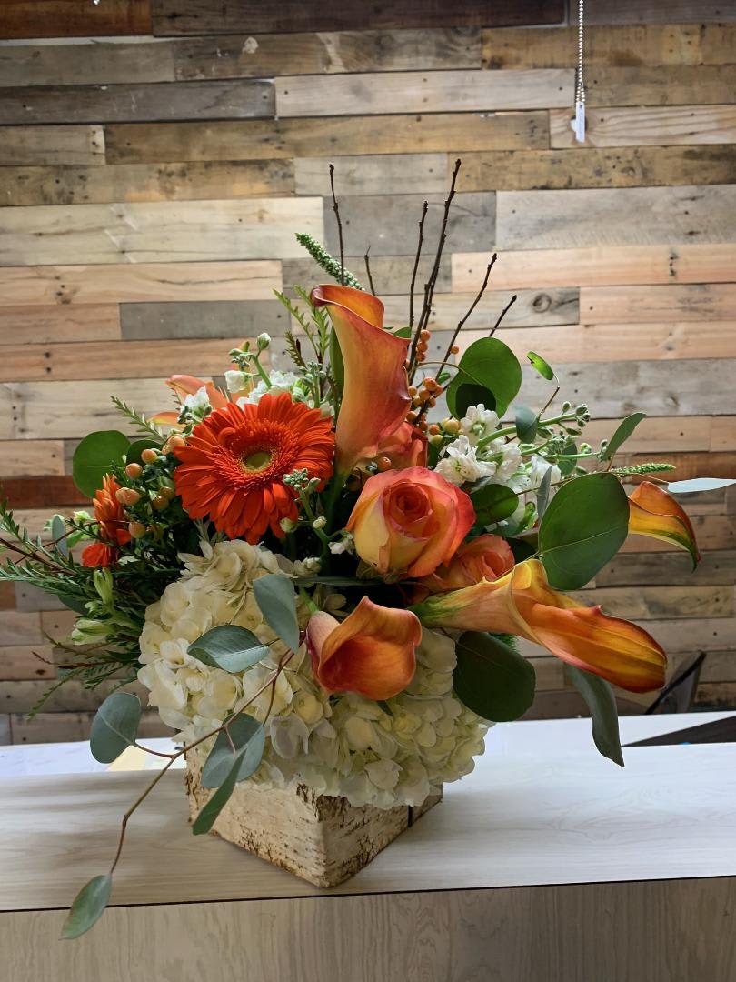 Thinking Fall - This burst of colorful flowers puts you in the tropics! In a birch box  or similar container, you will find a mix of Orange, whites, and greens of various flowers!