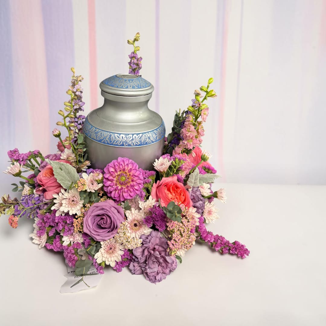 Floral arrangement around a silver urn with pink, purple, and white blooms