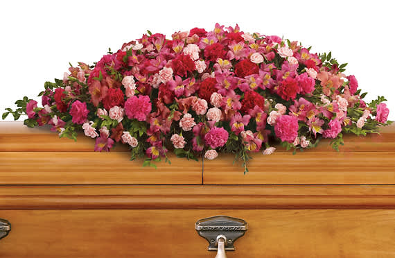 Pink and red floral spray on a wooden casket