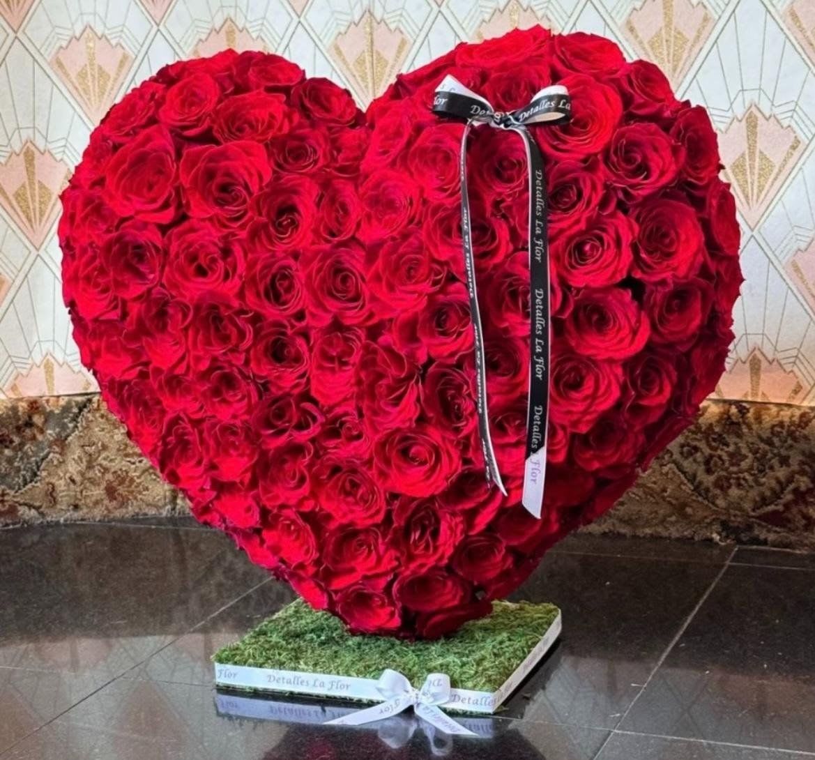 Heart-shaped arrangement of red roses with a ribbon on a square base