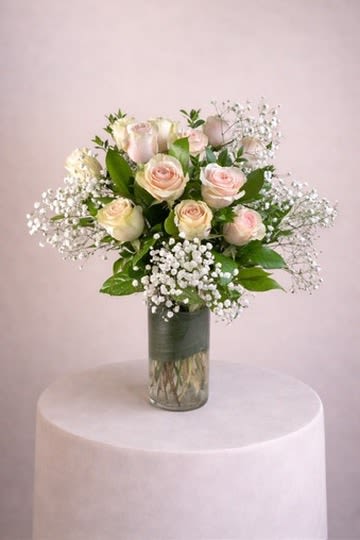Bouquet of pale pink roses and baby's breath in a glass vase