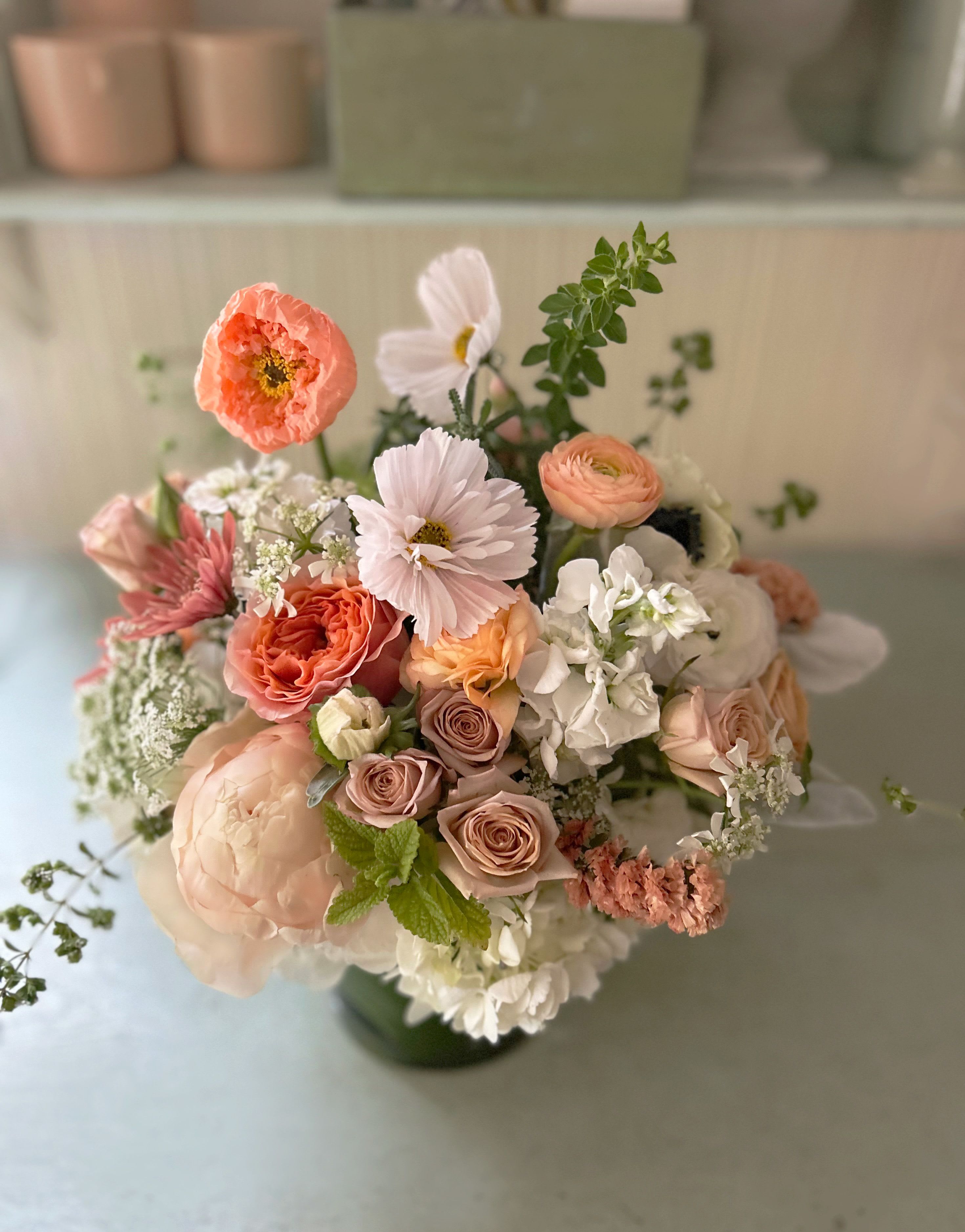 Wild Herbal - The super natural Wild Herbal arrangement is made with heavenly herbs and natural, seasonal stems like cosmos and poppies - and roses, ranunculus, peony (when in season) in muted, golden and green colors with white and ivory accents. So adorable, for all occasions. Placed in a clear lleaf lined 5" by 5" clear cylinder vase. Ready for hand delivery in LA.