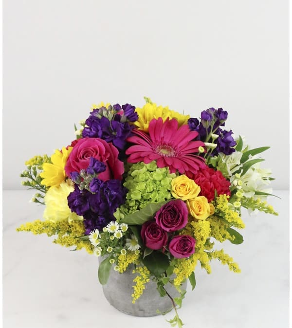 Colorful bouquet of roses, gerbera daisies, and mixed blooms in a gray vase