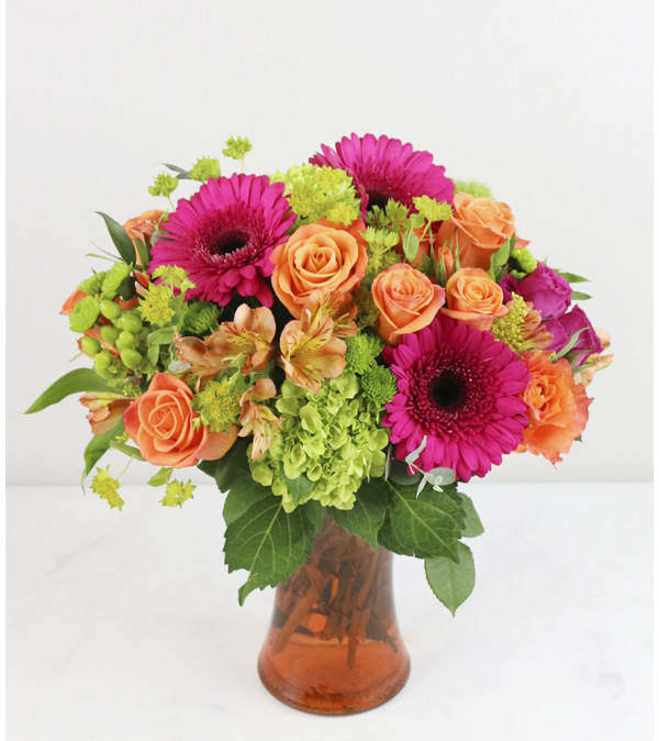 Bouquet of pink gerbera daisies and orange roses in an amber glass vase
