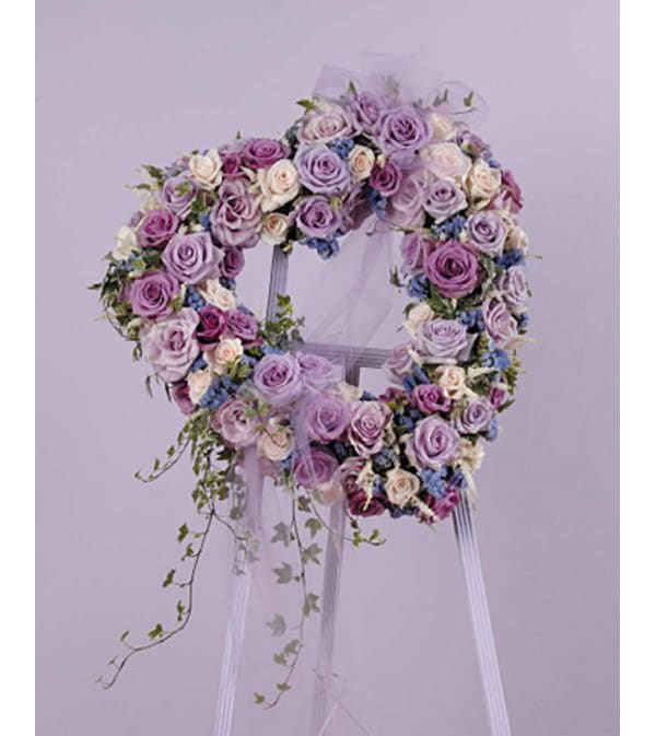Heart-shaped floral wreath of lavender and pink roses on a stand