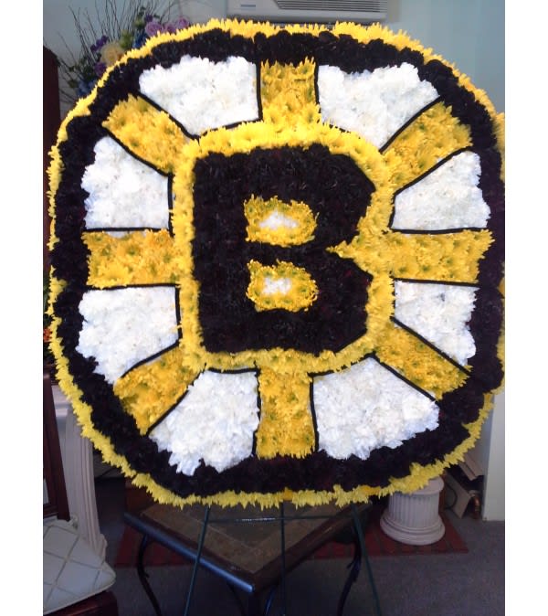 Large floral tribute shaped like a black and gold letter B