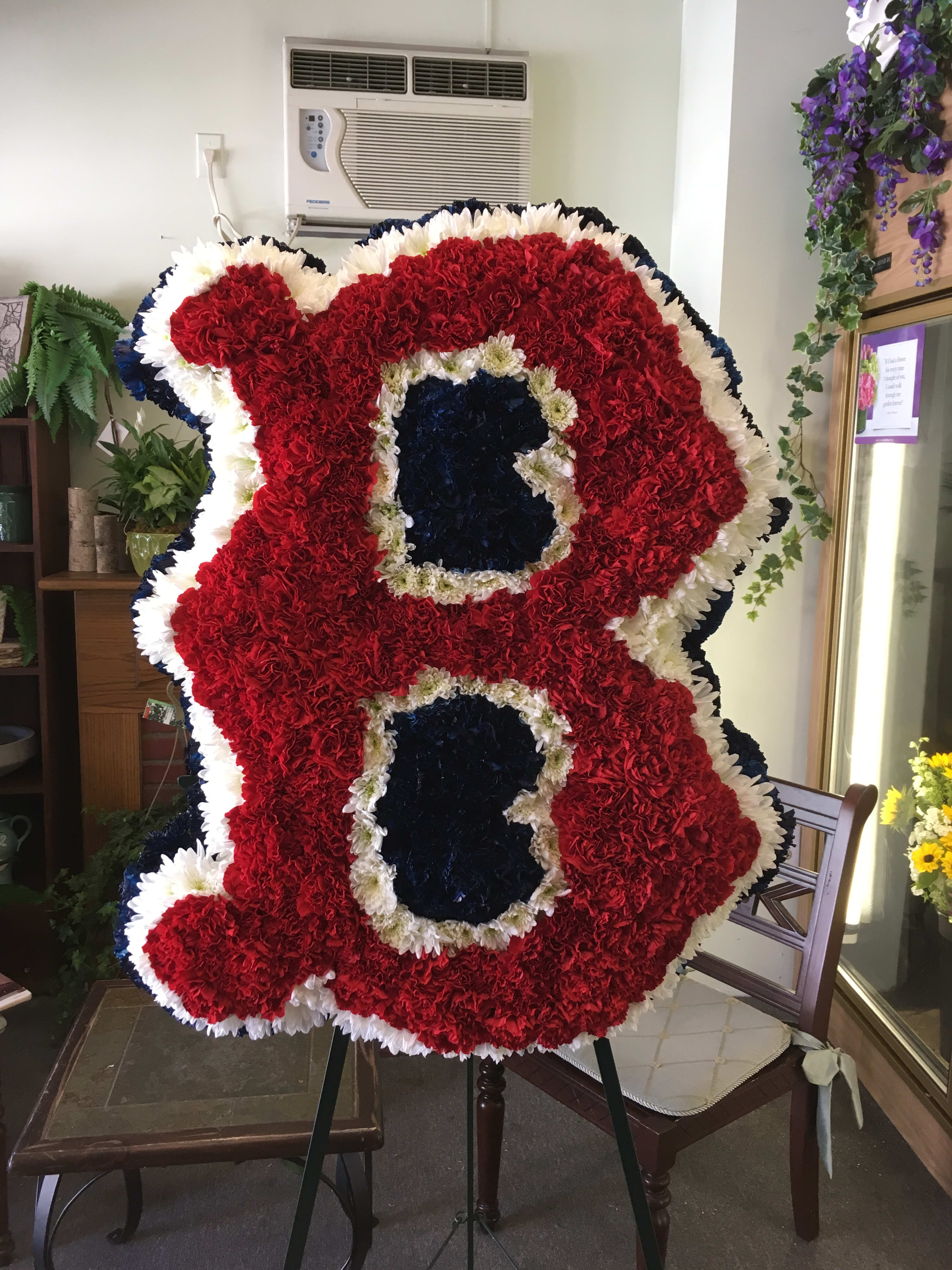 Large standing floral tribute shaped like the number 88 in red, white, and blue