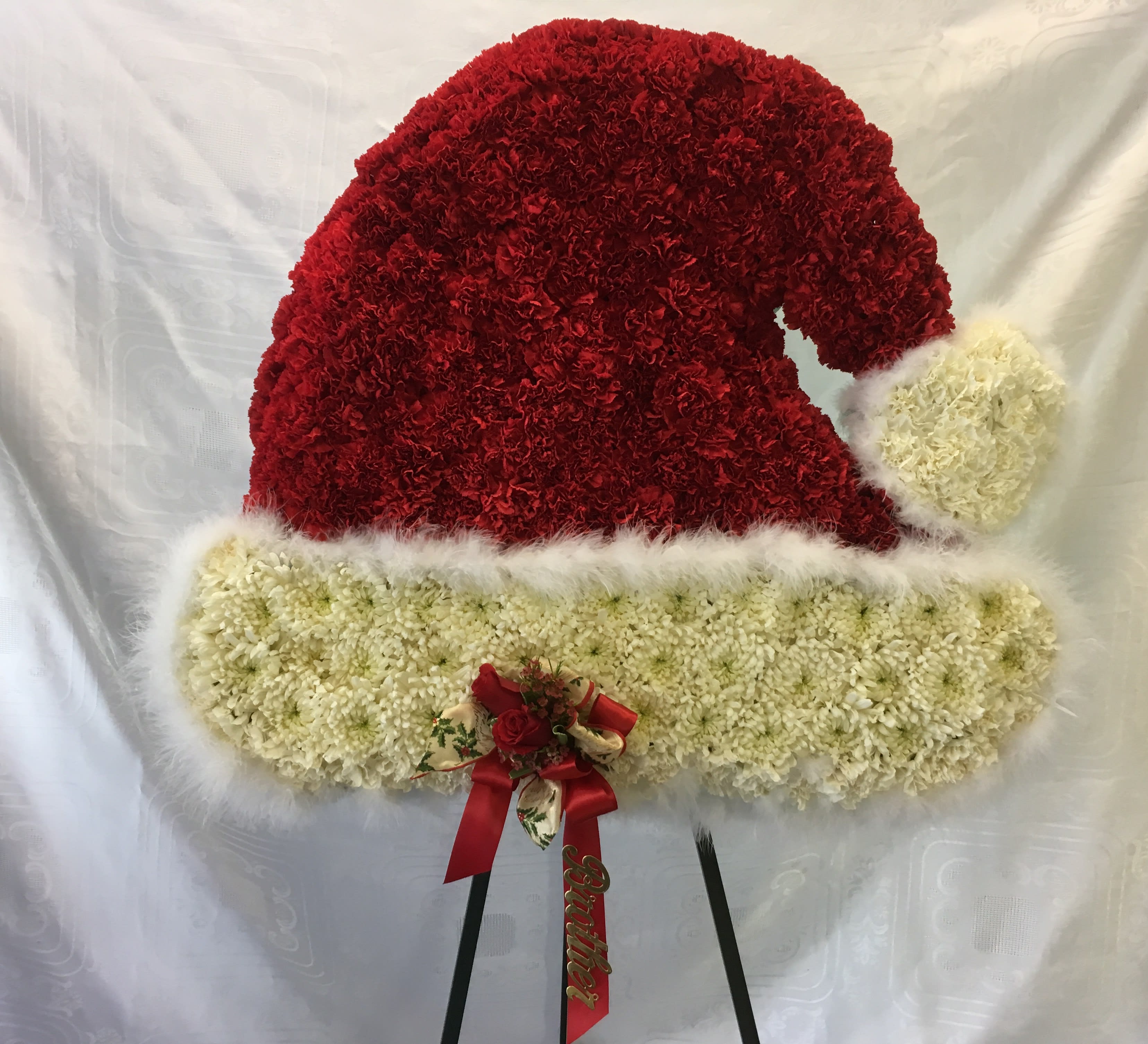 Red and white floral Santa hat on an easel
