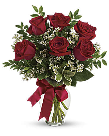 Bouquet of red roses in a clear glass vase with a burgundy ribbon
