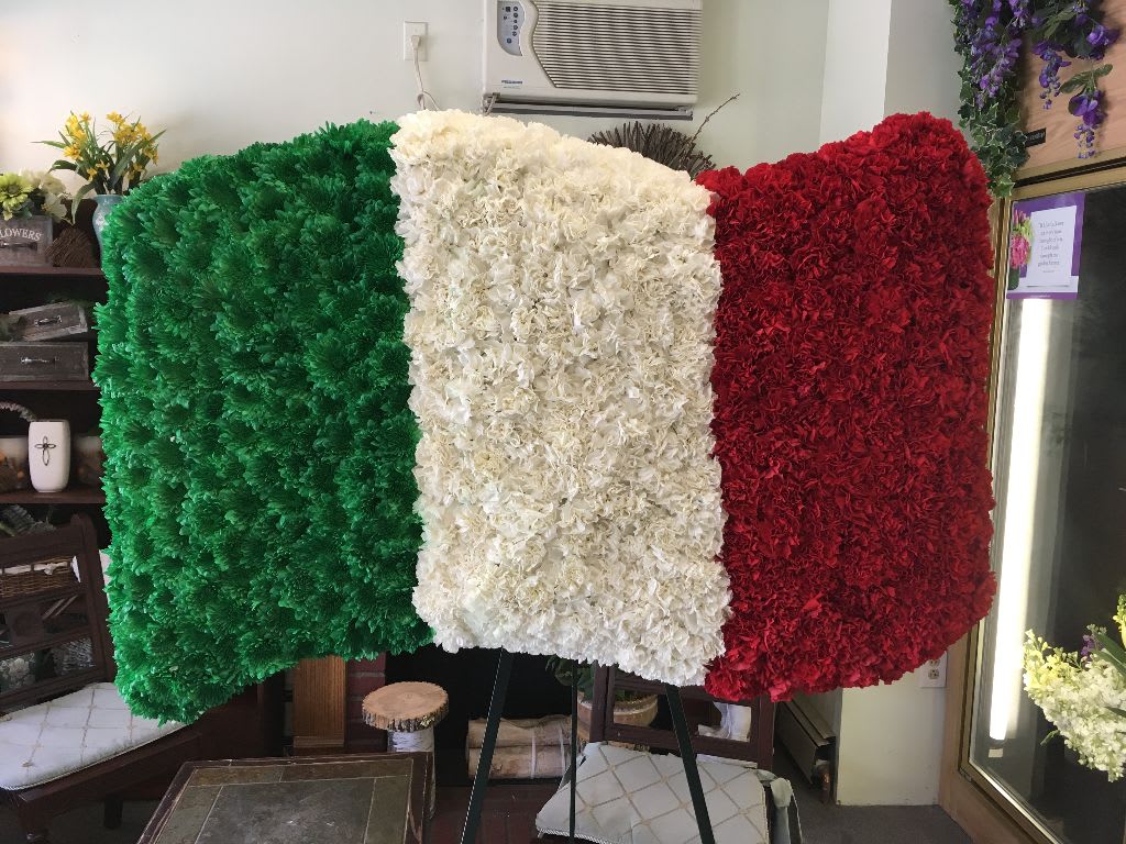 Floral display in green, white, and red arranged like a flag on an easel