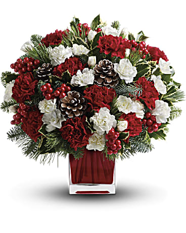 Red and white floral arrangement in a square glass vase with pinecones and berries