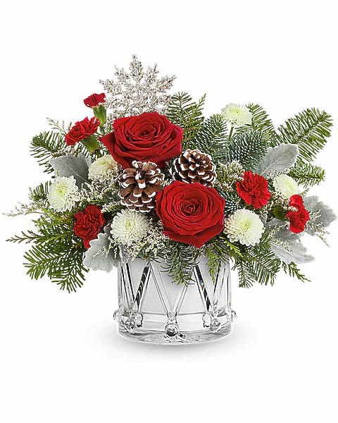 Red roses and white flowers in a clear glass vase with pinecones