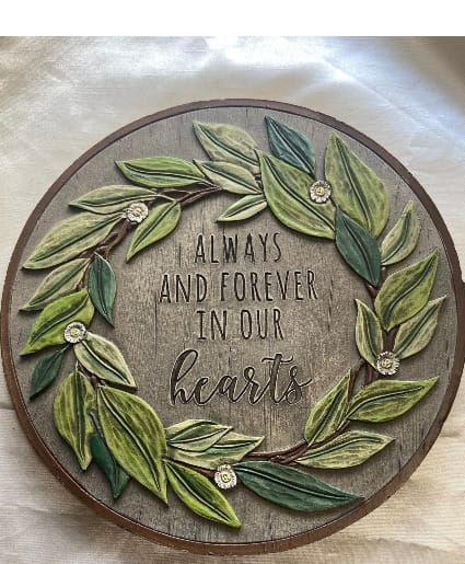 Round wooden wall sign with leafy wreath and the words "Always and Forever in Our Hearts"