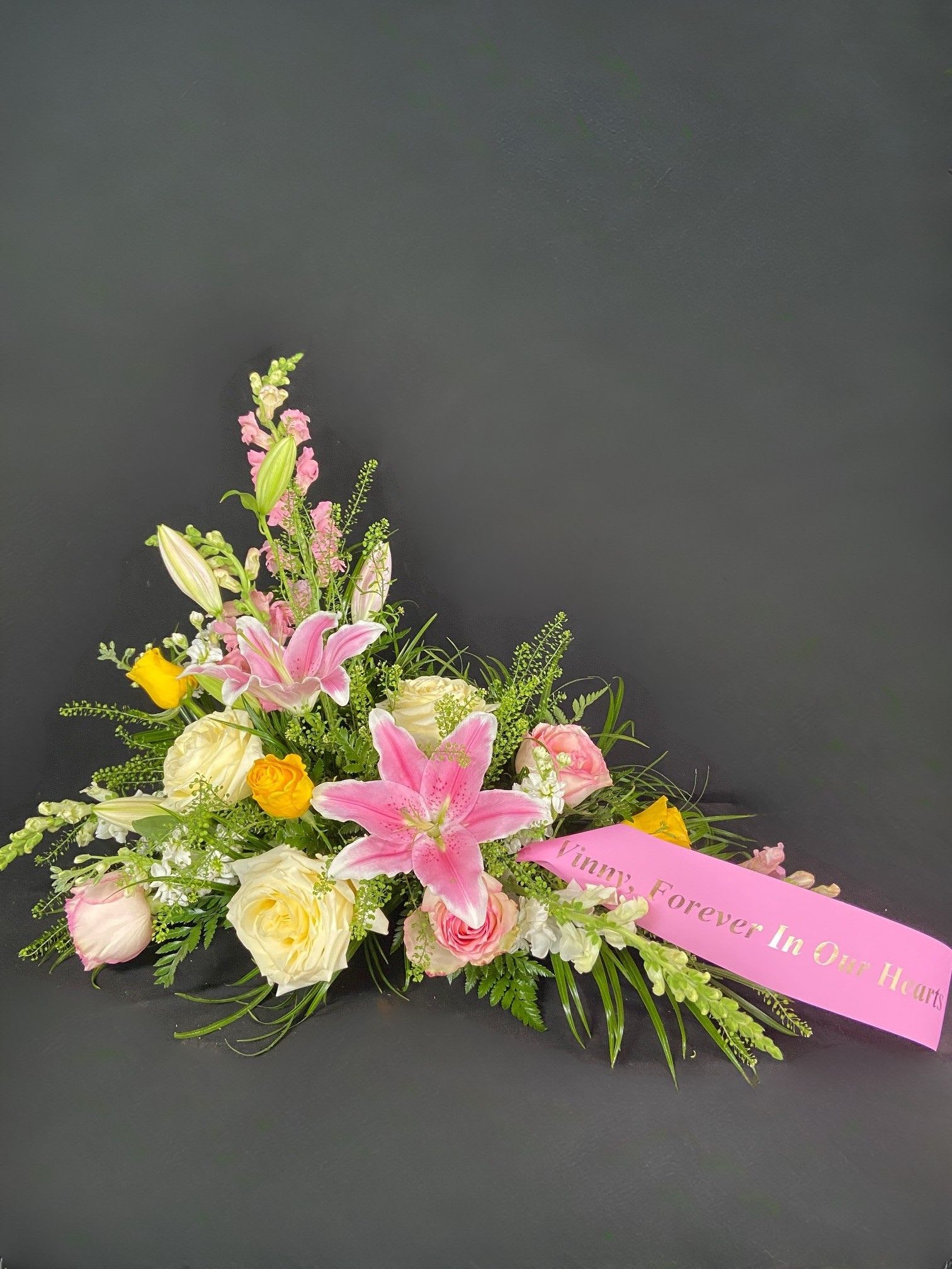 Pink lilies and roses arranged with a memorial ribbon