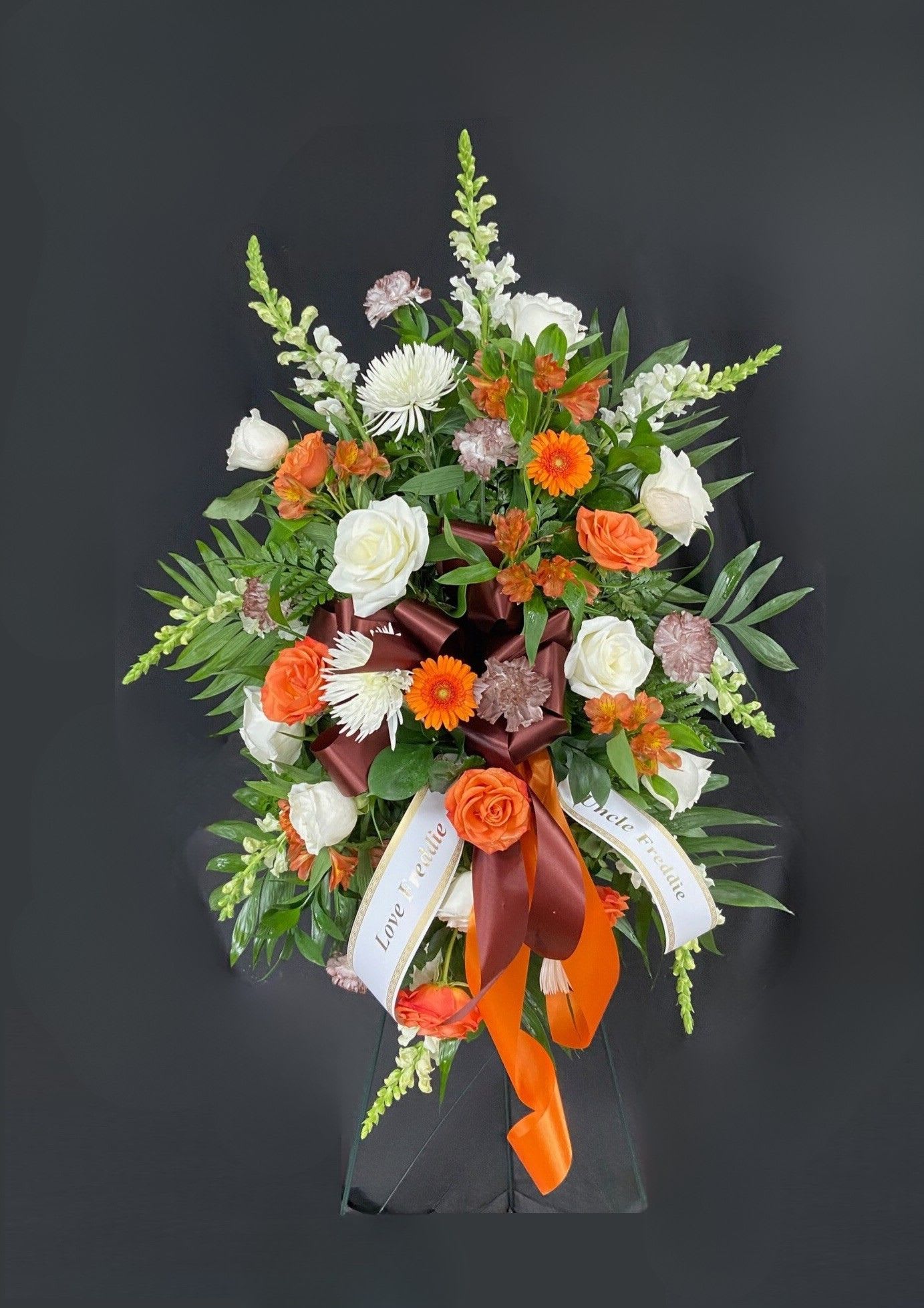 Standing floral spray with white and orange blooms and ribbon accents