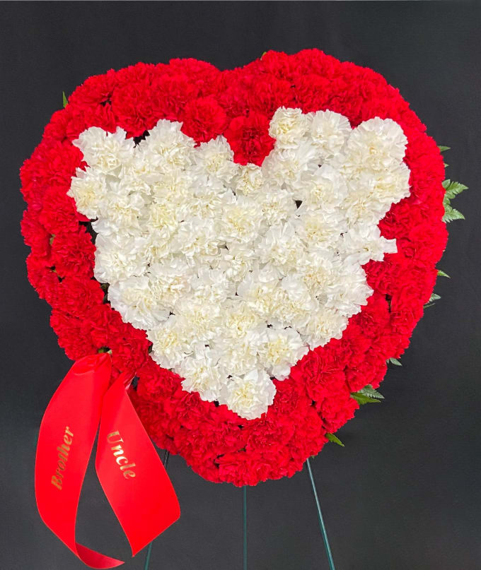 Heart-shaped red and white carnation wreath with a red ribbon