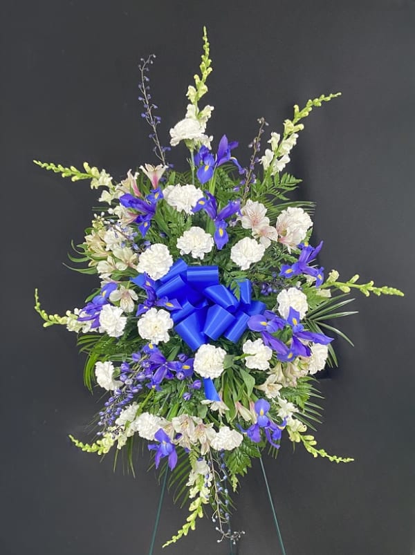 Standing floral spray with white and purple flowers and a blue ribbon