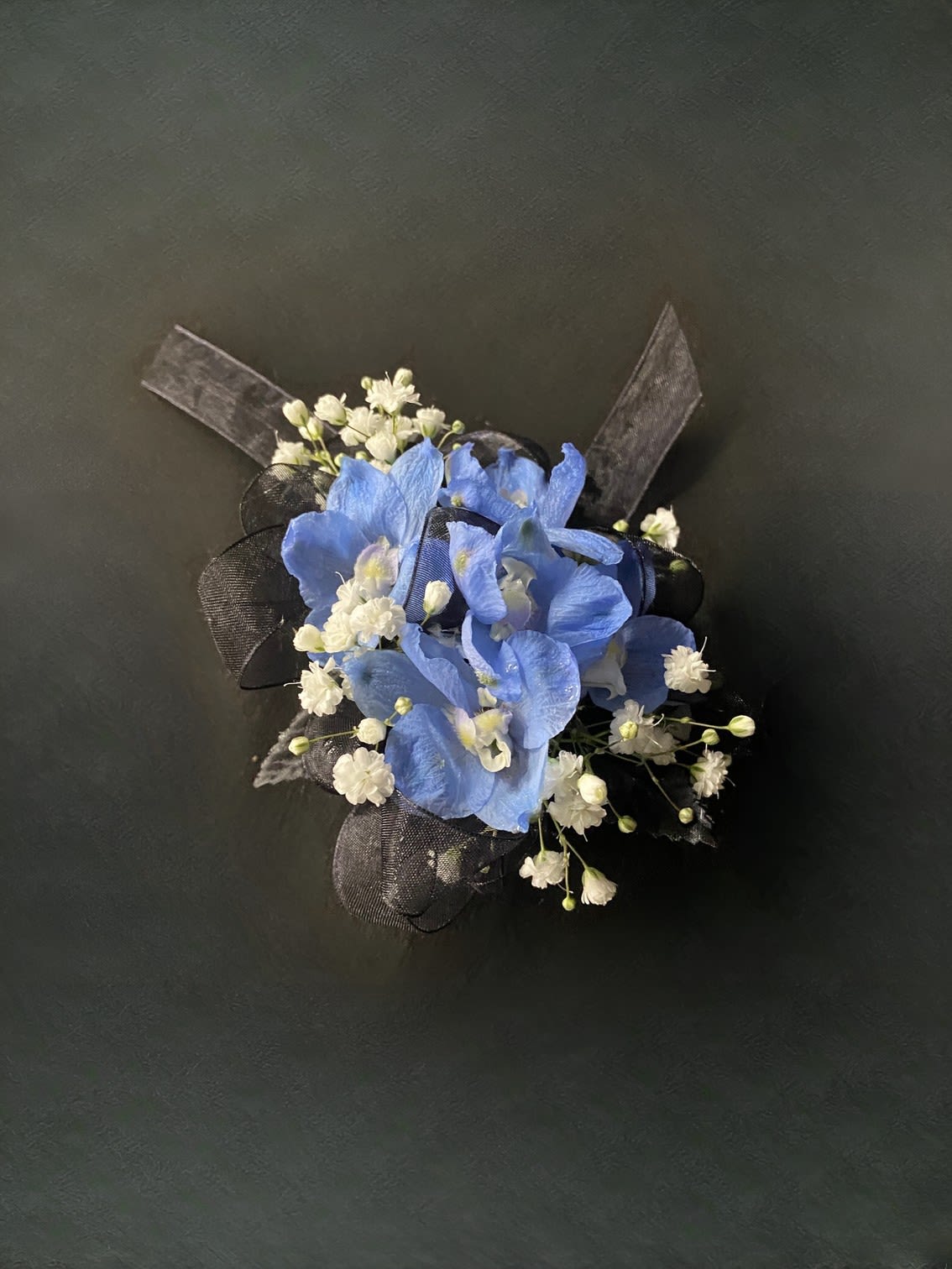 Light Blue Delphinium Corsage - A naturally blue flower that will compliment any outfit. The only flower color option for this boutonniere is light blue. Please select the wristlet color and up to 2 ribbon colors from the add-on selections you would like included. (Please do not select any of the flower color options)