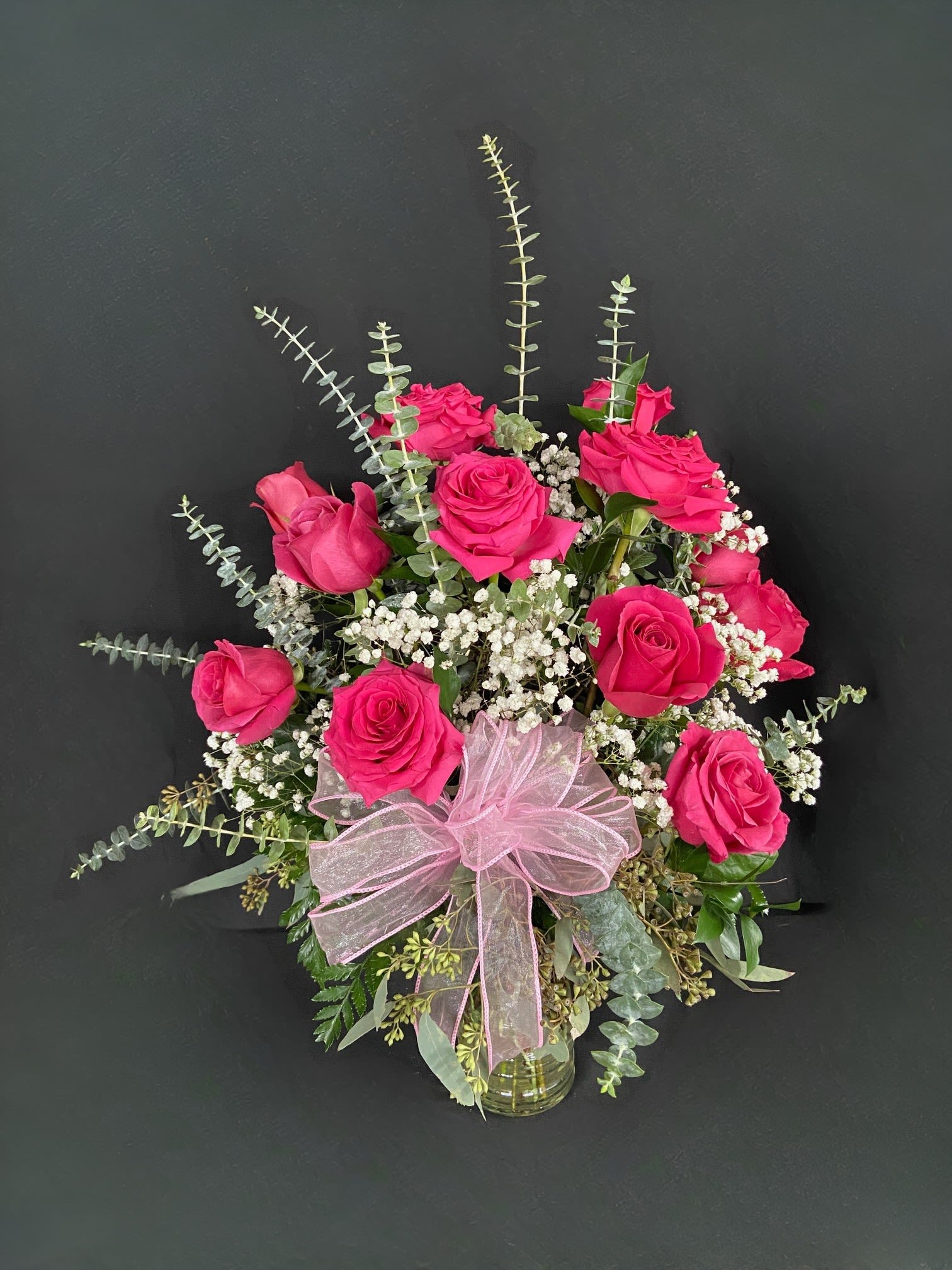 Pink rose bouquet with baby's breath in a glass vase and pink ribbon