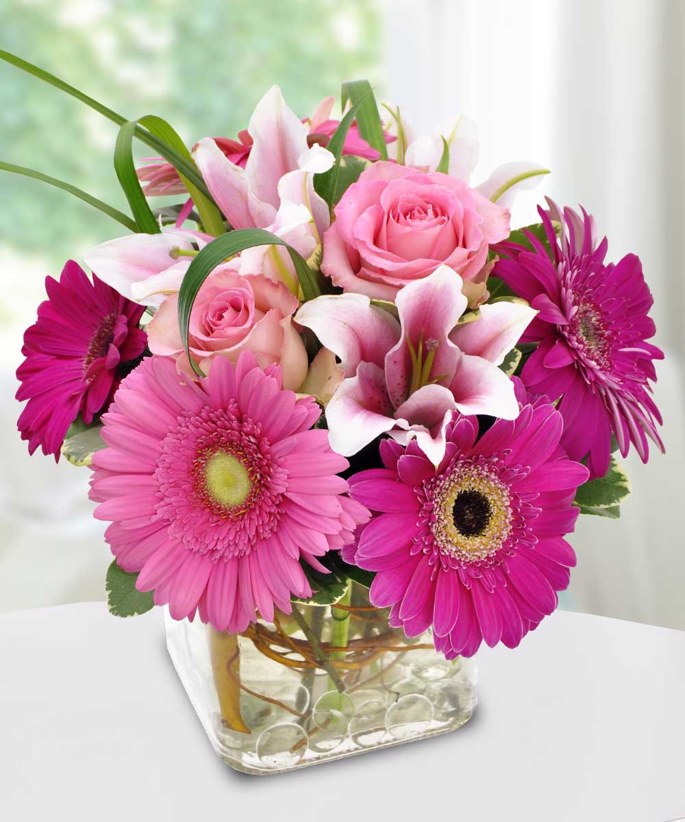 Pink roses and lilies with magenta gerbera daisies in a glass vase
